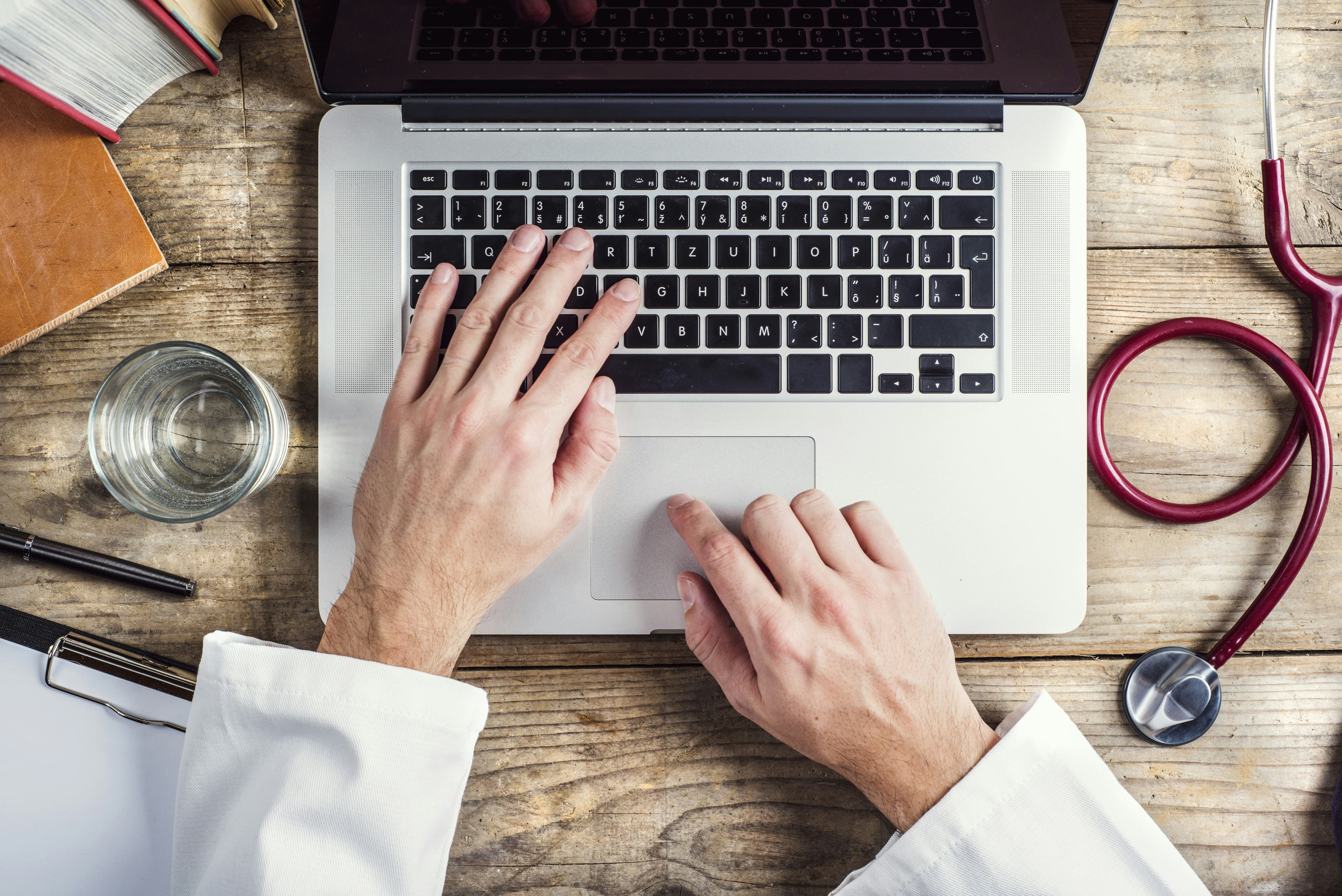 A person using a laptop with a supportive team in the background